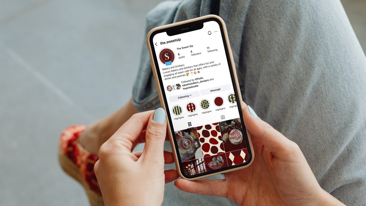 A person holding a smartphone displays an Instagram profile featuring circular patterns and red, white, and green designs in the photo grid.