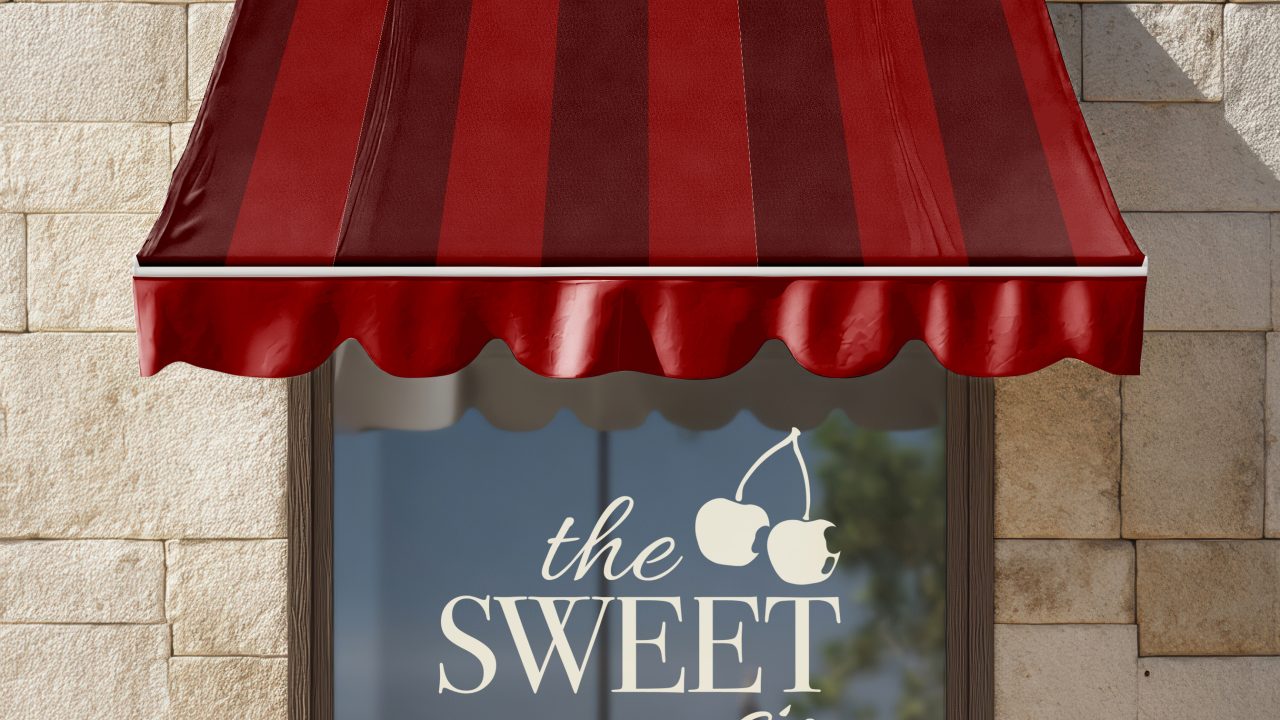 A red striped awning shades a window with the SWEET sip and two cherry graphics printed on the glass, mounted on a light stone wall.