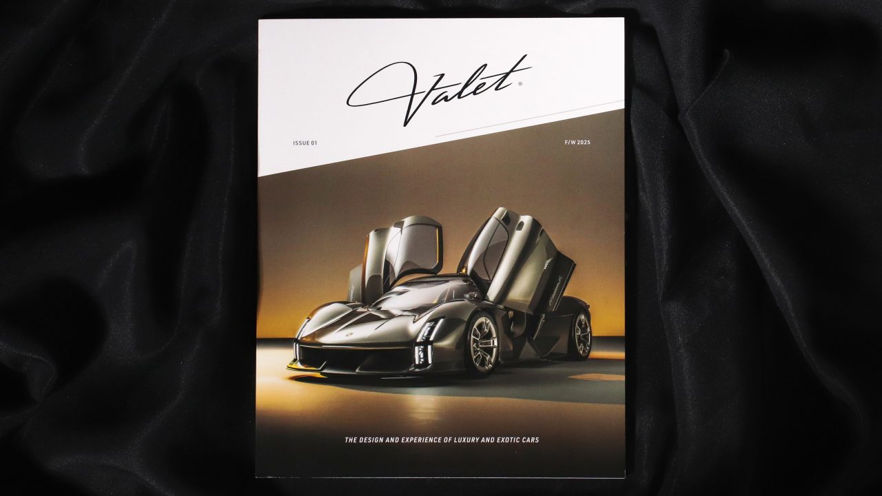 A magazine titled Valet featuring a luxury sports car with its doors open, placed on a black fabric background.