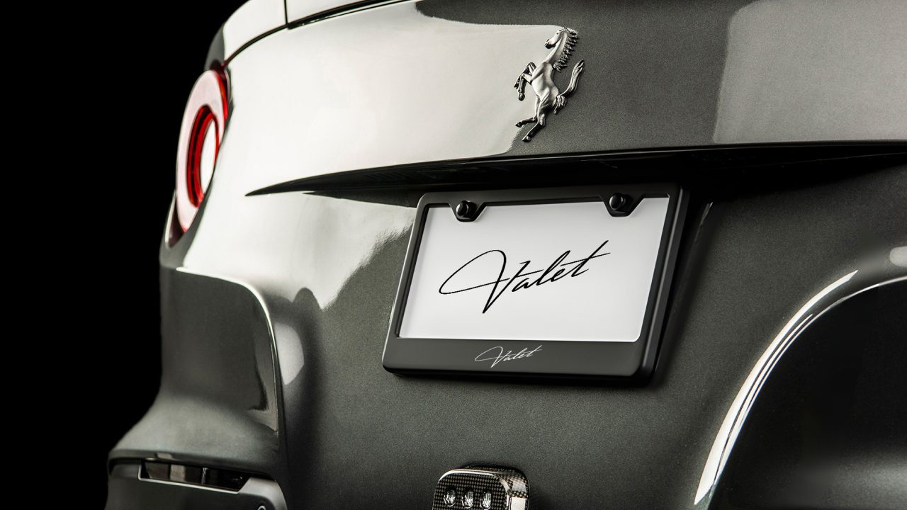 Close-up of the rear of a grey Ferrari with a license plate that reads “Valet” in script font.