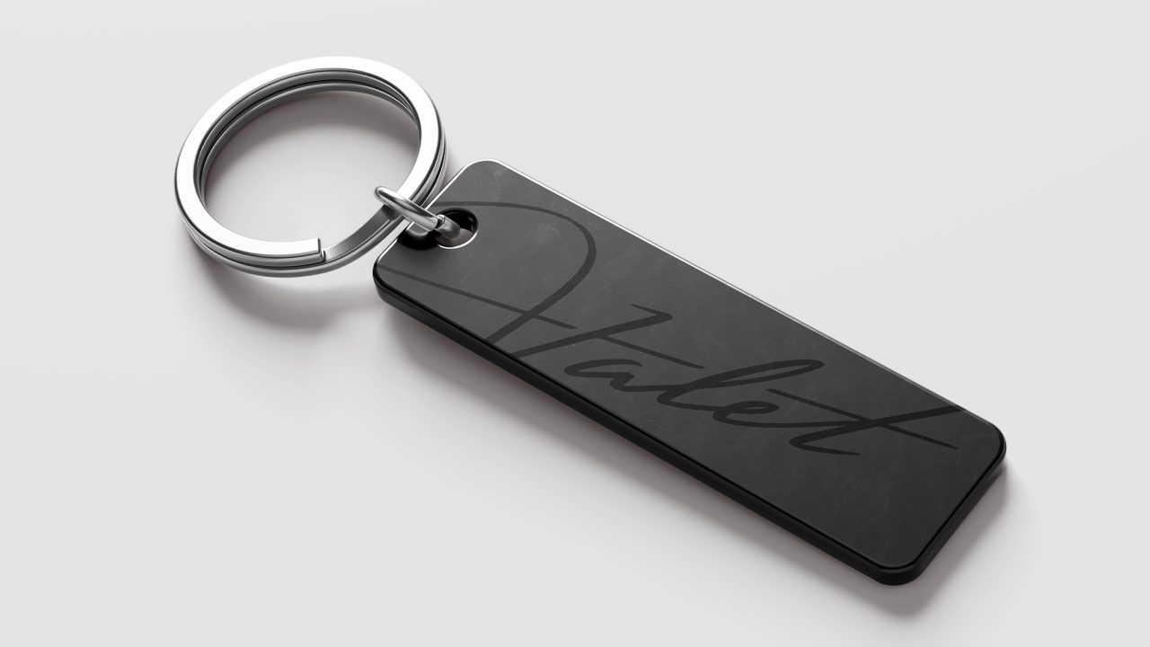 A black rectangular keychain with the word Valet written in cursive script, attached to a silver key ring, on a plain white background.