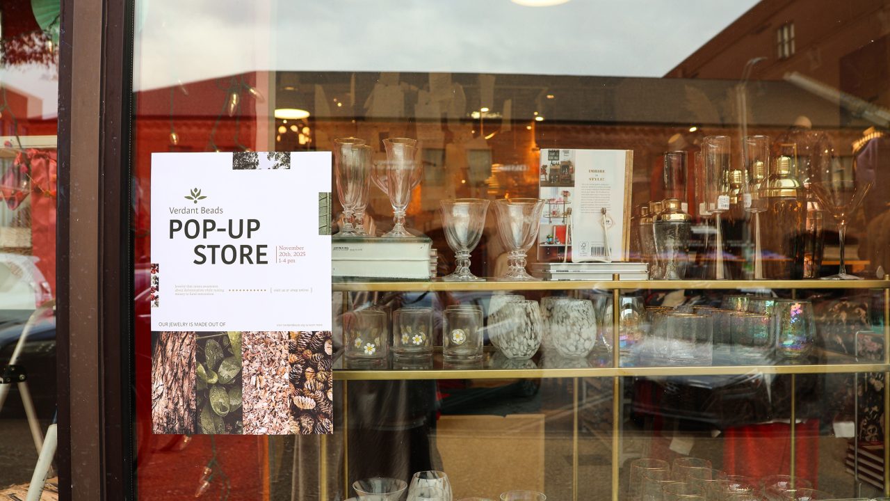A glass storefront displays assorted glassware and bottles on shelves; a poster on the window advertises a Verdant Beads pop-up store.