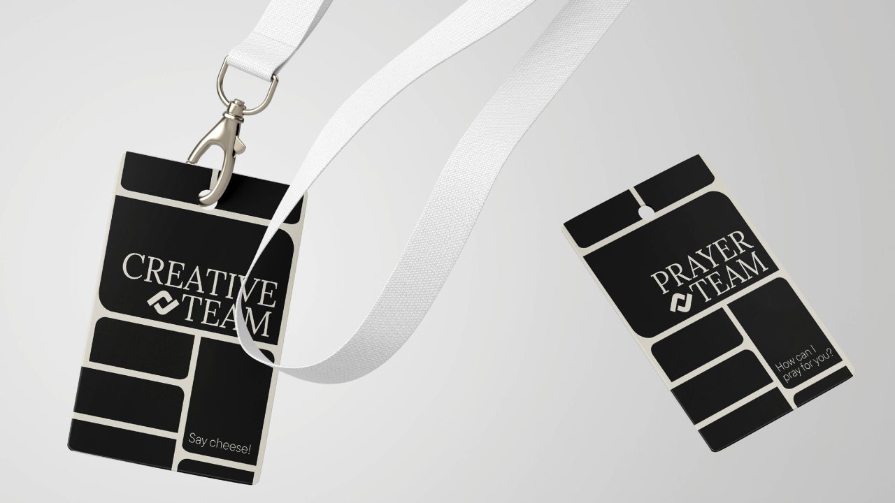 Two black name badges with white lanyards are labeled Creative Team and Prayer Team on a light background.