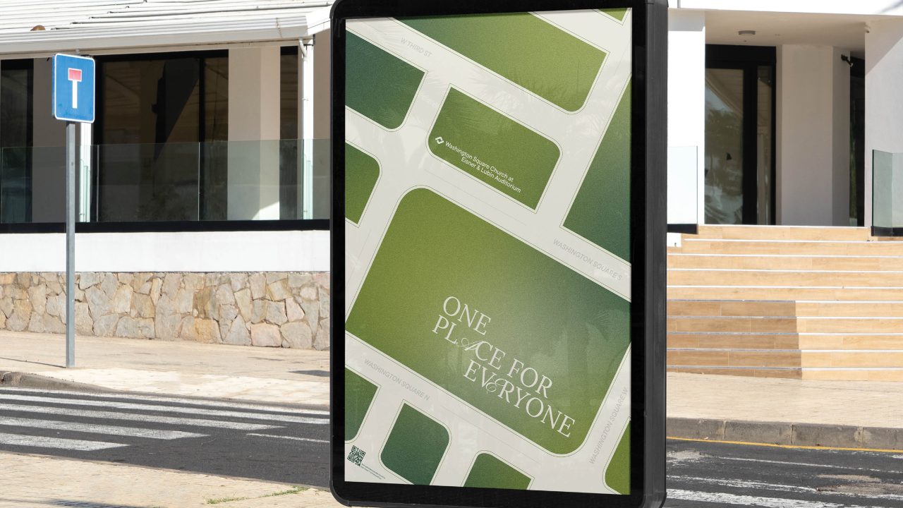 A street-side billboard displays a map-themed advertisement with the text One Place For Everyone in front of a modern building and stone wall.