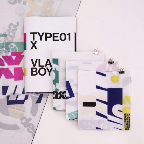 A booklet labeled TYPE01 X VLAD BOY and three clipped documents with abstract, layered text and geometric graphics are arranged on a surface with similar printed designs.