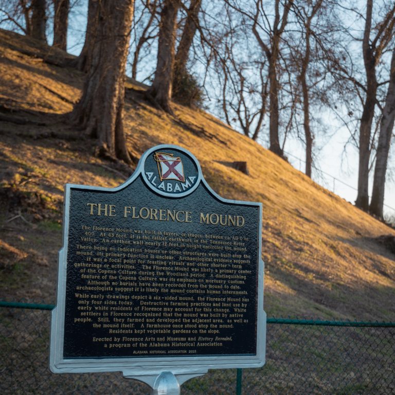 A historical marker titled The Florence Mound stands in front of a grassy hill with leafless trees in Florence, Alabama, describing the significance of the mound.