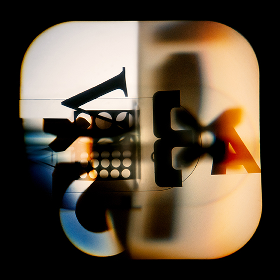 Abstract composition of overlapping letters, numbers, and geometric shapes in black and red tones, with light and shadow effects dividing the image vertically.