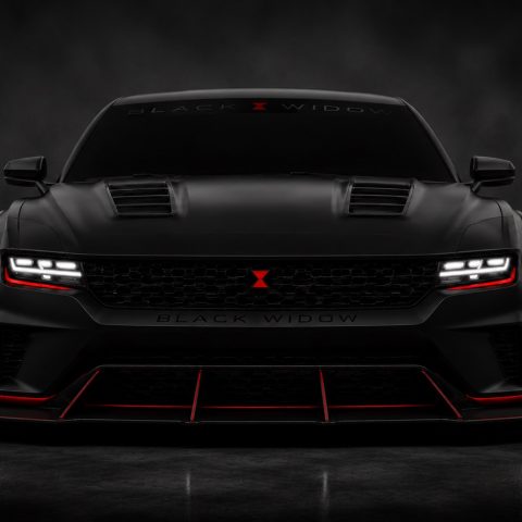 Matte black sports car with red accents, aggressive front grille, LED headlights, and Black Widow branding on a dark, smoky background.