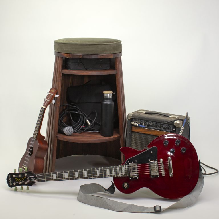 A red electric guitar, small ukulele, amplifier, stool, microphone, cable, and water bottle arranged together on a white background.