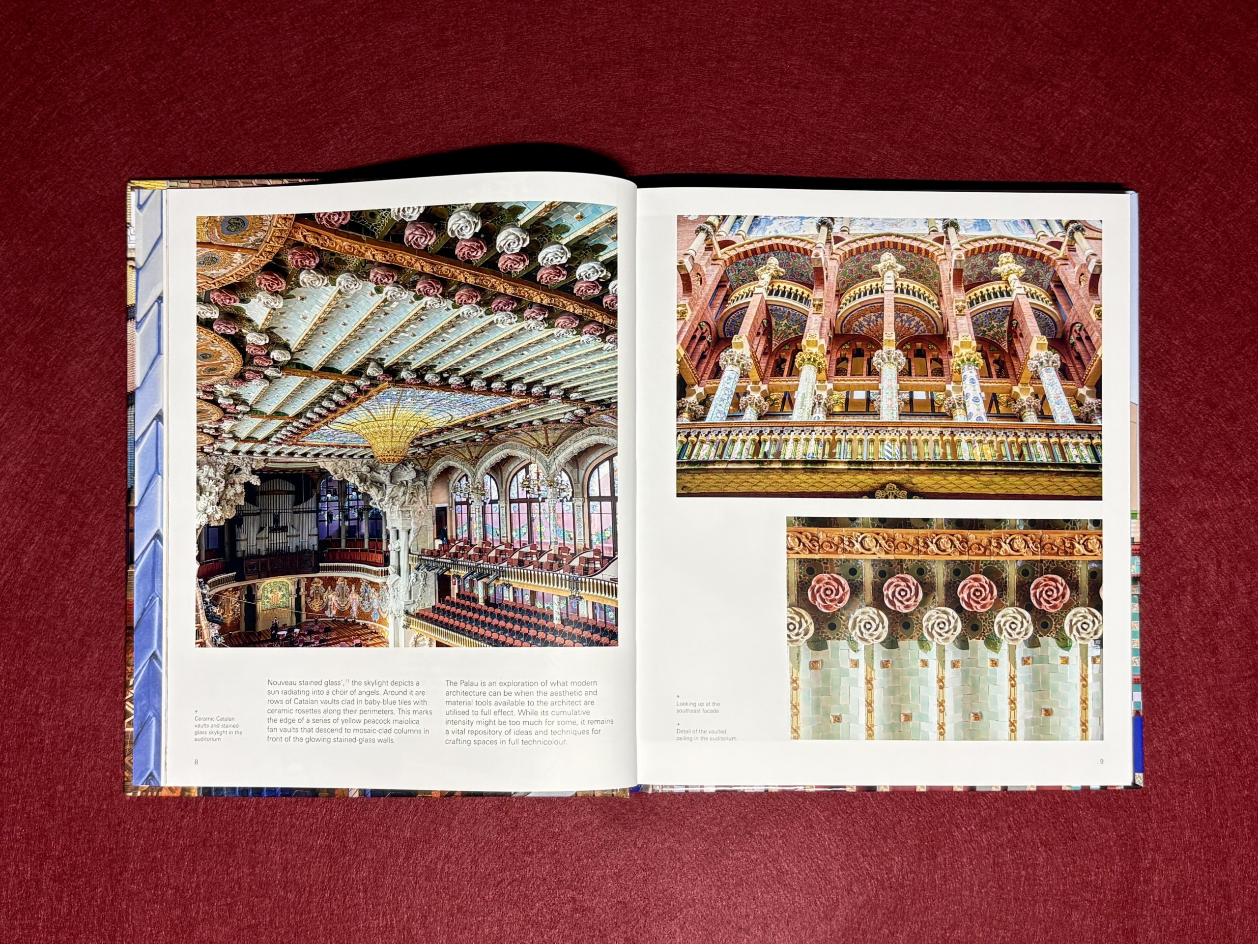 An open book displays colorful photos of ornate architectural interiors, including detailed ceilings, balconies, columns, and decorative patterns, against a red textured surface.
