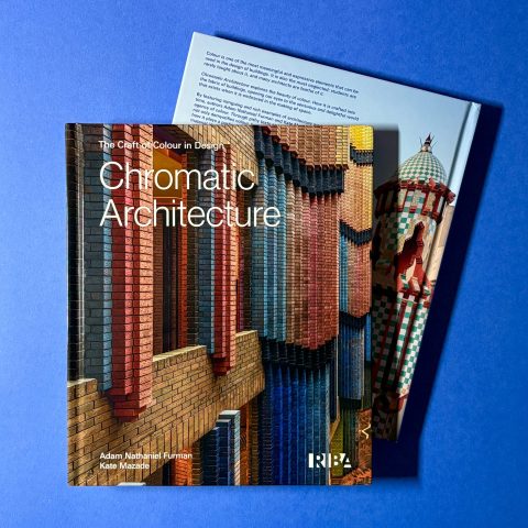 A book titled Chromatic Architecture lies on top of an open magazine, both displayed on a blue surface.